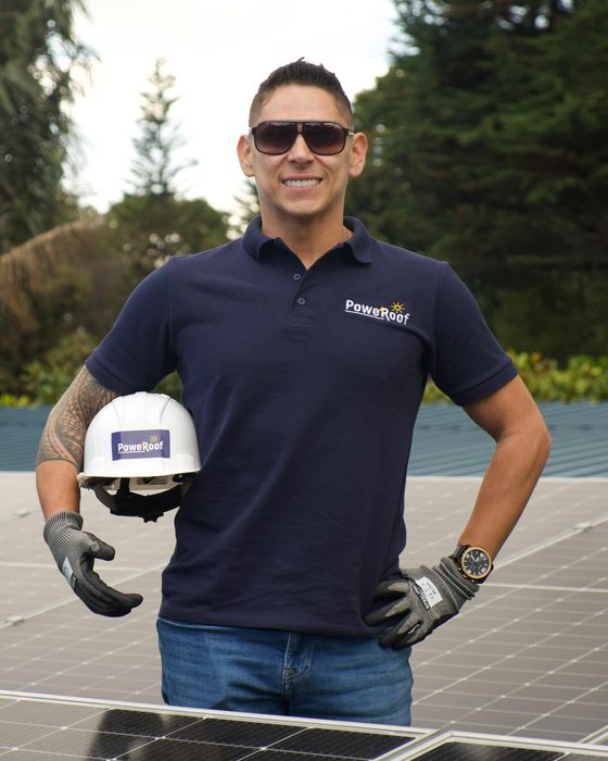 Especialista de PoweRoof con el polo y el casco de la marca, sobre un techo con paneles solares