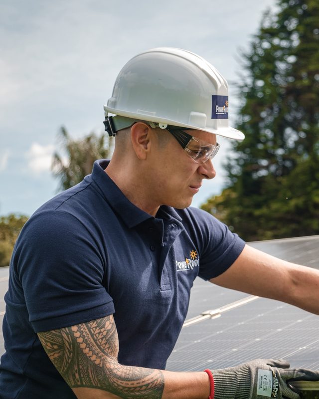 Técnico de PoweRoof con casco y gafas de seguridad revisando un panel solar