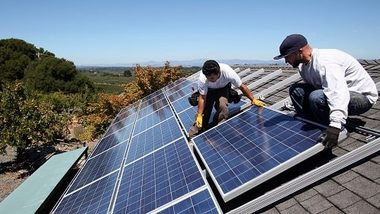 Dos instaladores de PoweRoof montando paneles solares en el techo de una casa