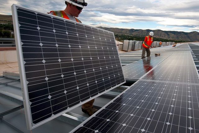 Operarios montando paneles solares sobre la cubierta de un edificio